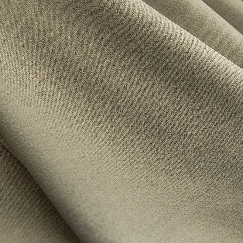 Close-up of beige blackout curtain fabric with soft, textured thermal weave folds.