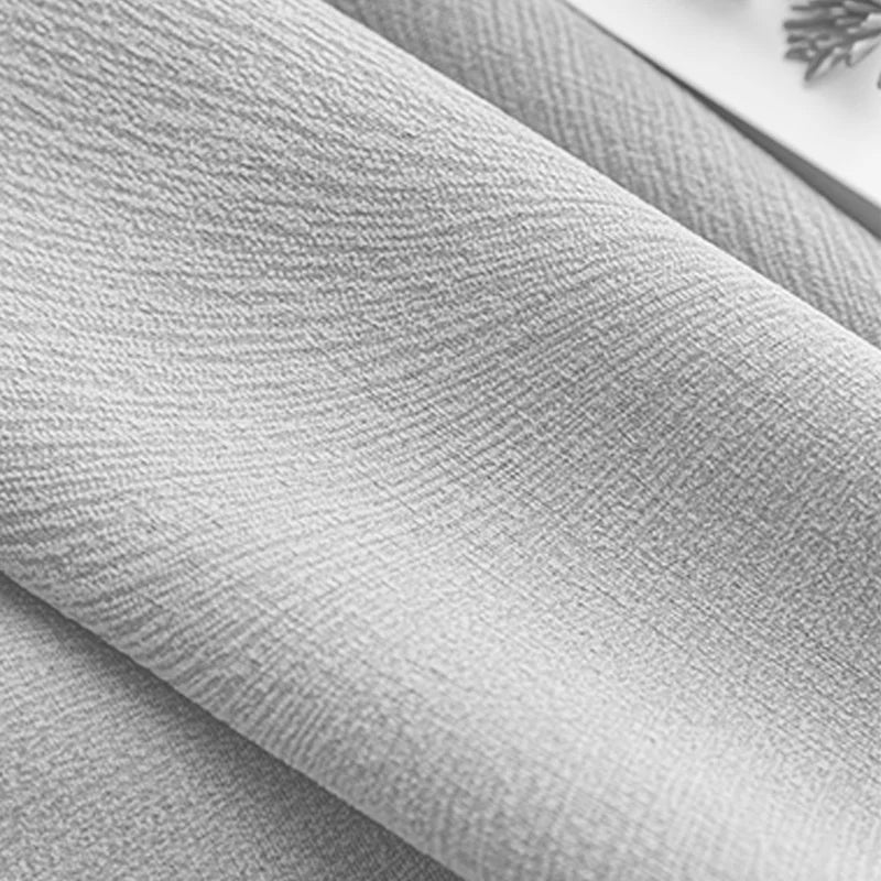 Close-up of light grey textured blackout curtain fabric with subtle weave pattern.