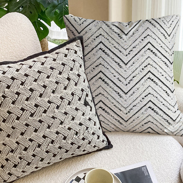 Cozy living room with two patterned throw pillows, white curtains, and a checkered cup on a tray.