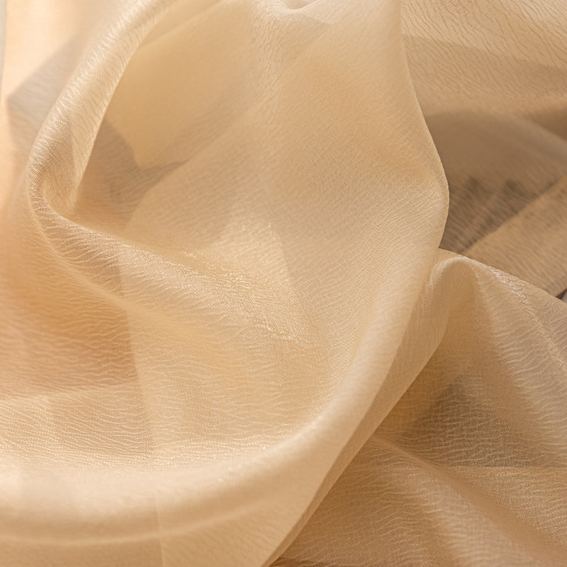 Close-up of beige sheer curtain fabric with soft light and textured weave.