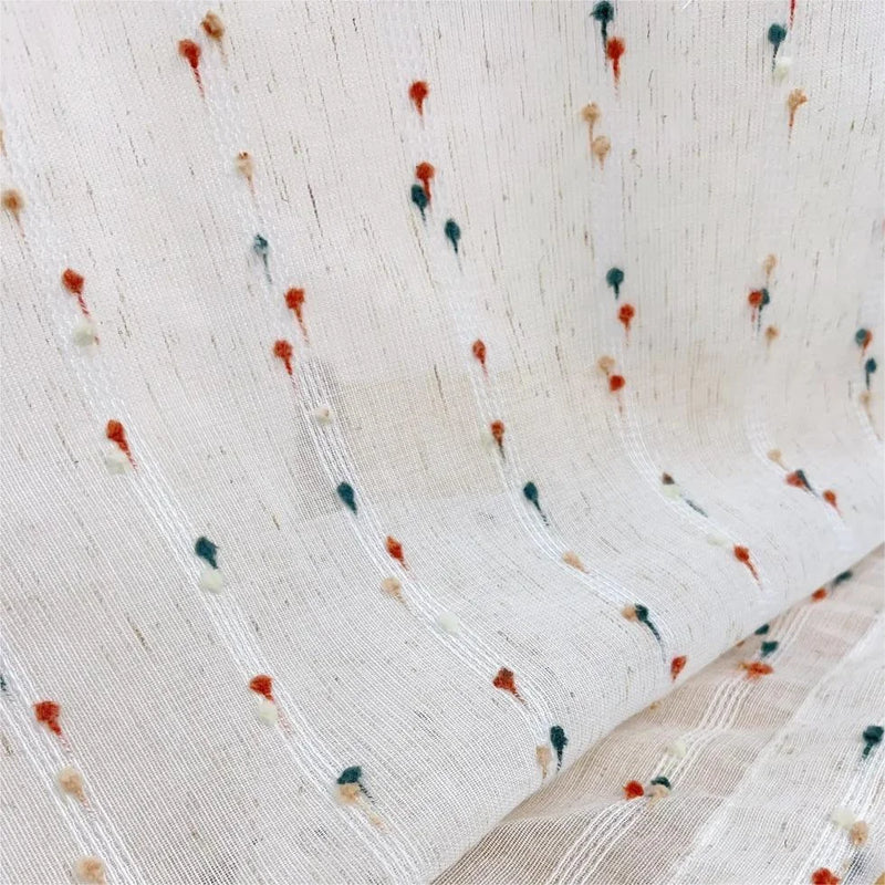 Sheer white curtain fabric with colorful embroidered dots and vertical textured stripes