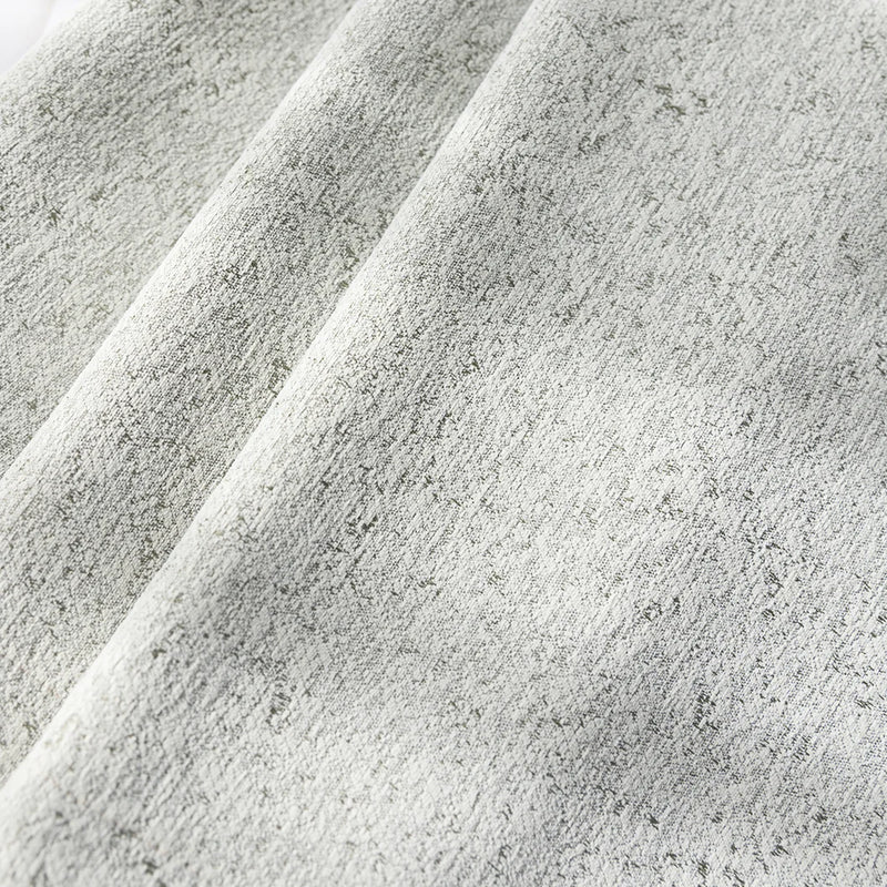 Close-up of textured light grey blackout curtain fabric with subtle pattern folds