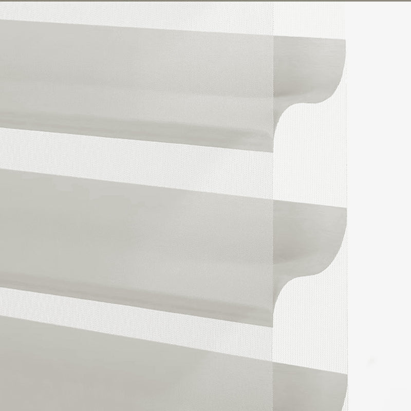 Close-up of layered sheer and opaque curtain fabric in light grey, modern window treatment