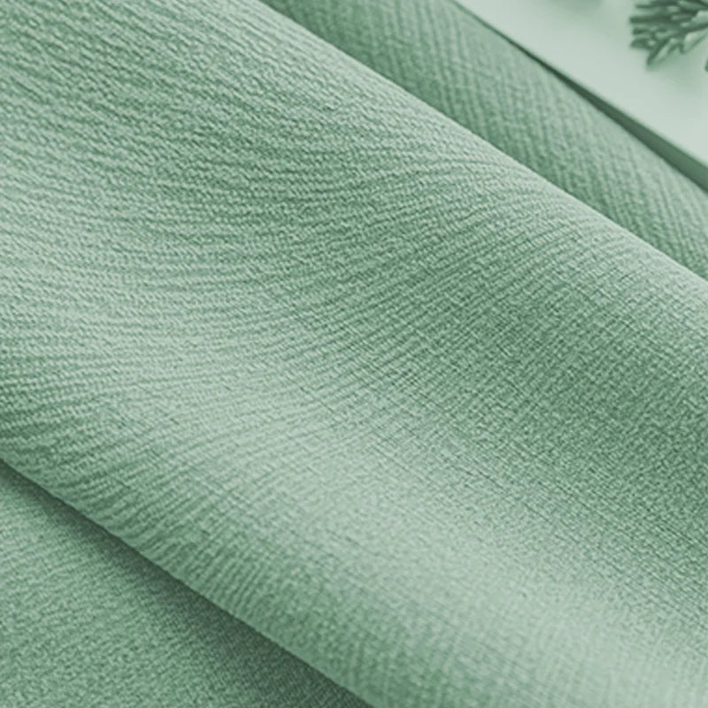 Close-up of light green textured blackout curtain fabric with soft folds
