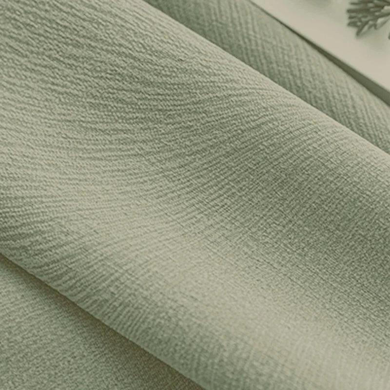 Close-up of textured light green blackout curtain fabric with soft folds