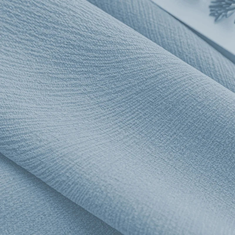 Close-up of textured light blue blackout curtain fabric, smooth and soft for window treatments