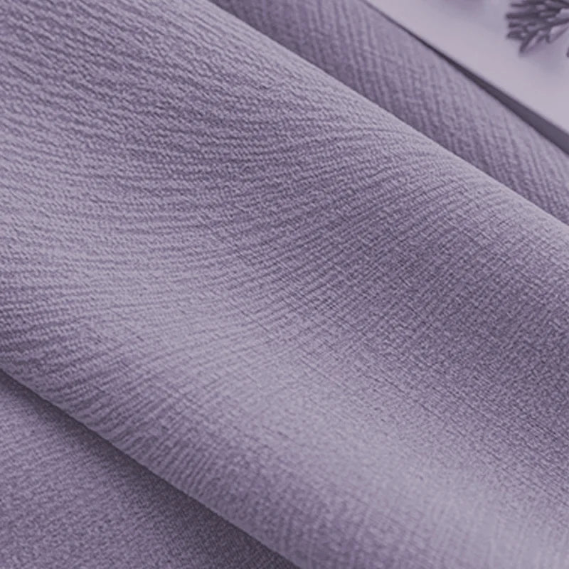 Close-up of textured lavender blackout curtain fabric with soft folds.