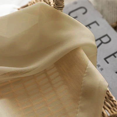 Beige French sheer curtain fabric draped over a basket, showcasing its light texture.