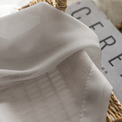 Light grey French sheer curtain fabric draped in a basket, soft and semi-transparent texture
