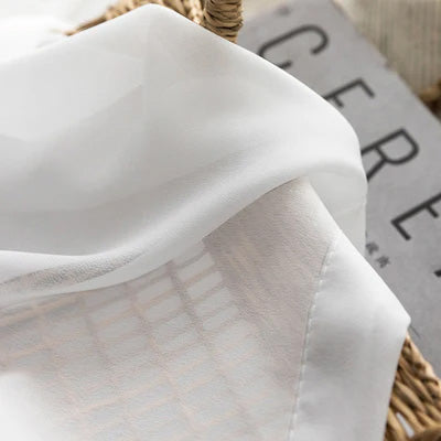 White French sheer curtain fabric with delicate semi-transparent texture on a wicker basket
